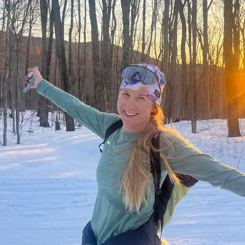 Skier enjoying sunset in a snowy forest