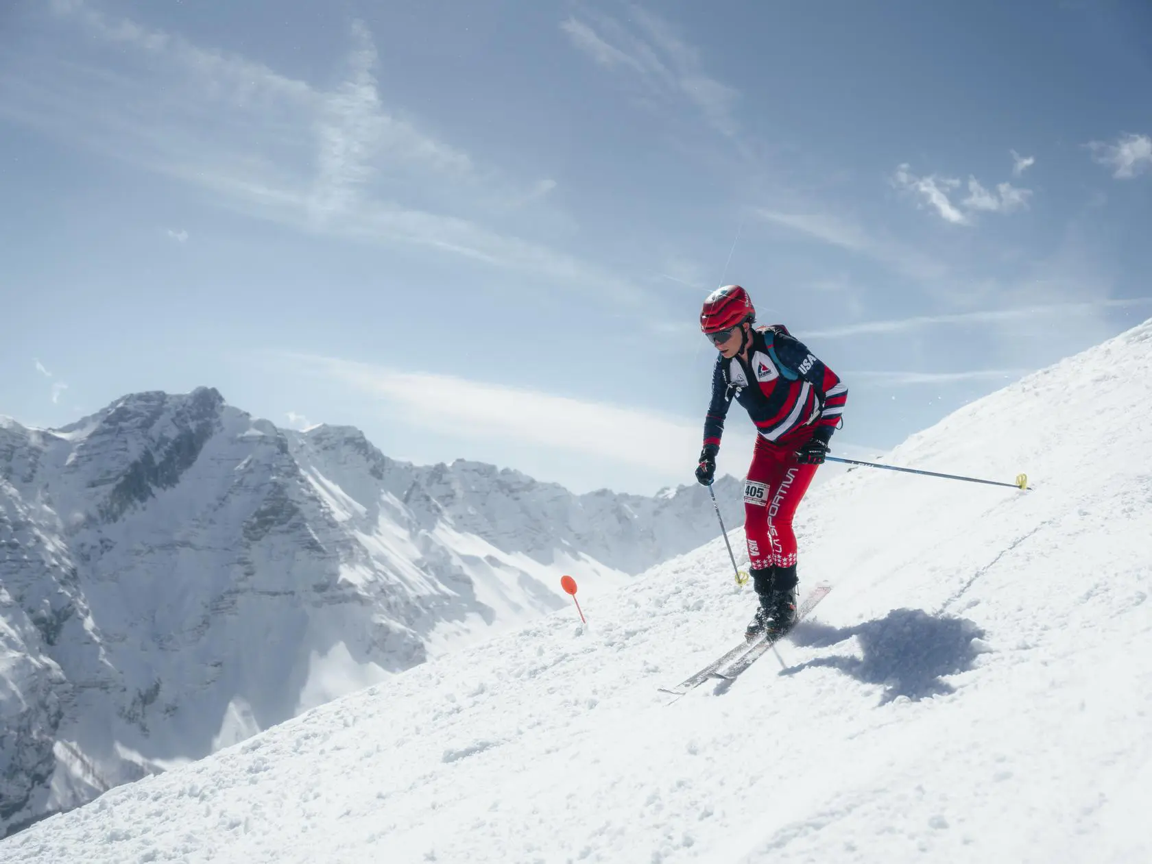 Athlete skiing downhill with mountains in background