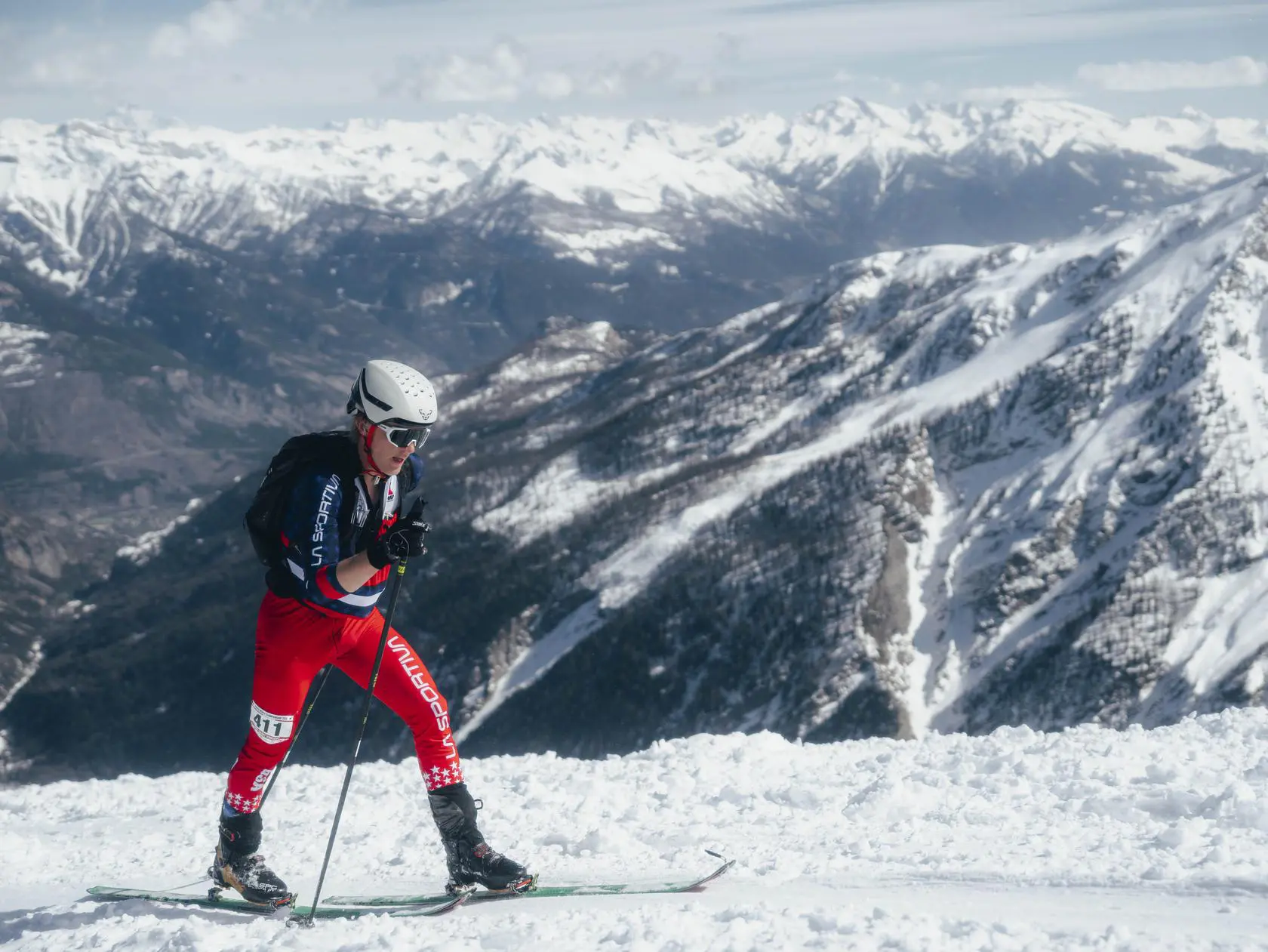 Ski mountaineer climbing snowy slope, mountain view