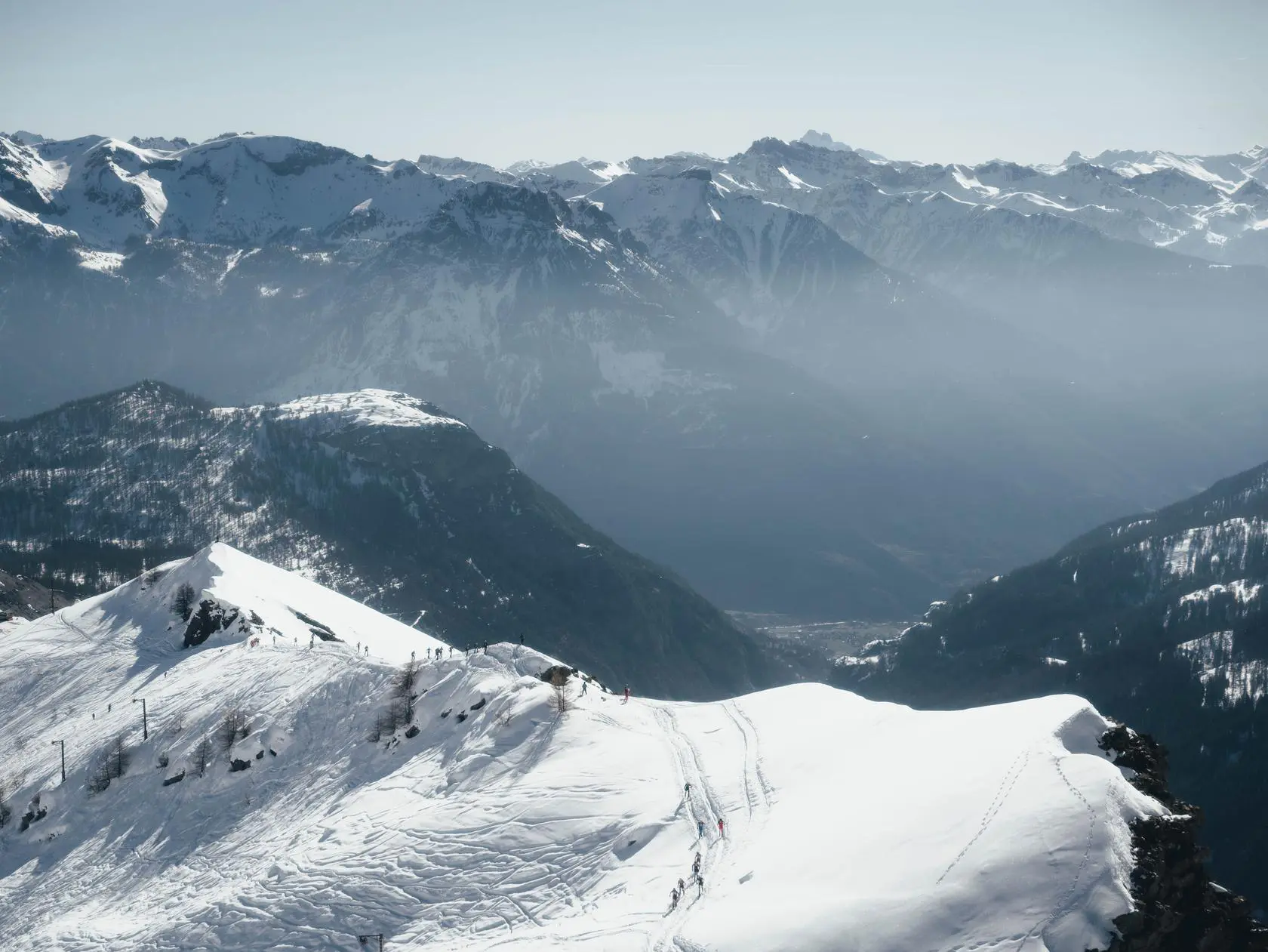 Winter mountain landscape with skiers and valley