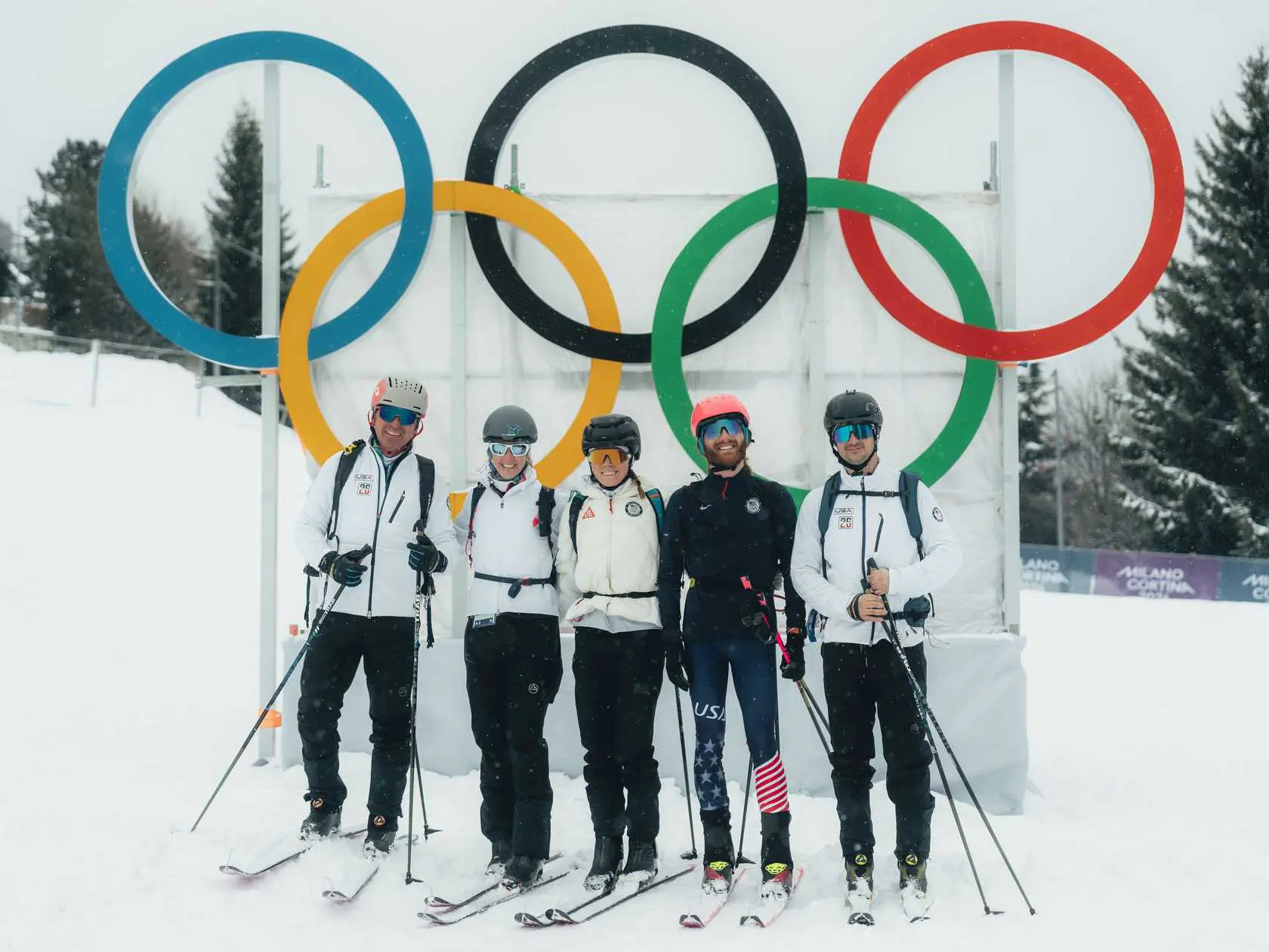 Skiers pose under Olympic rings in snow