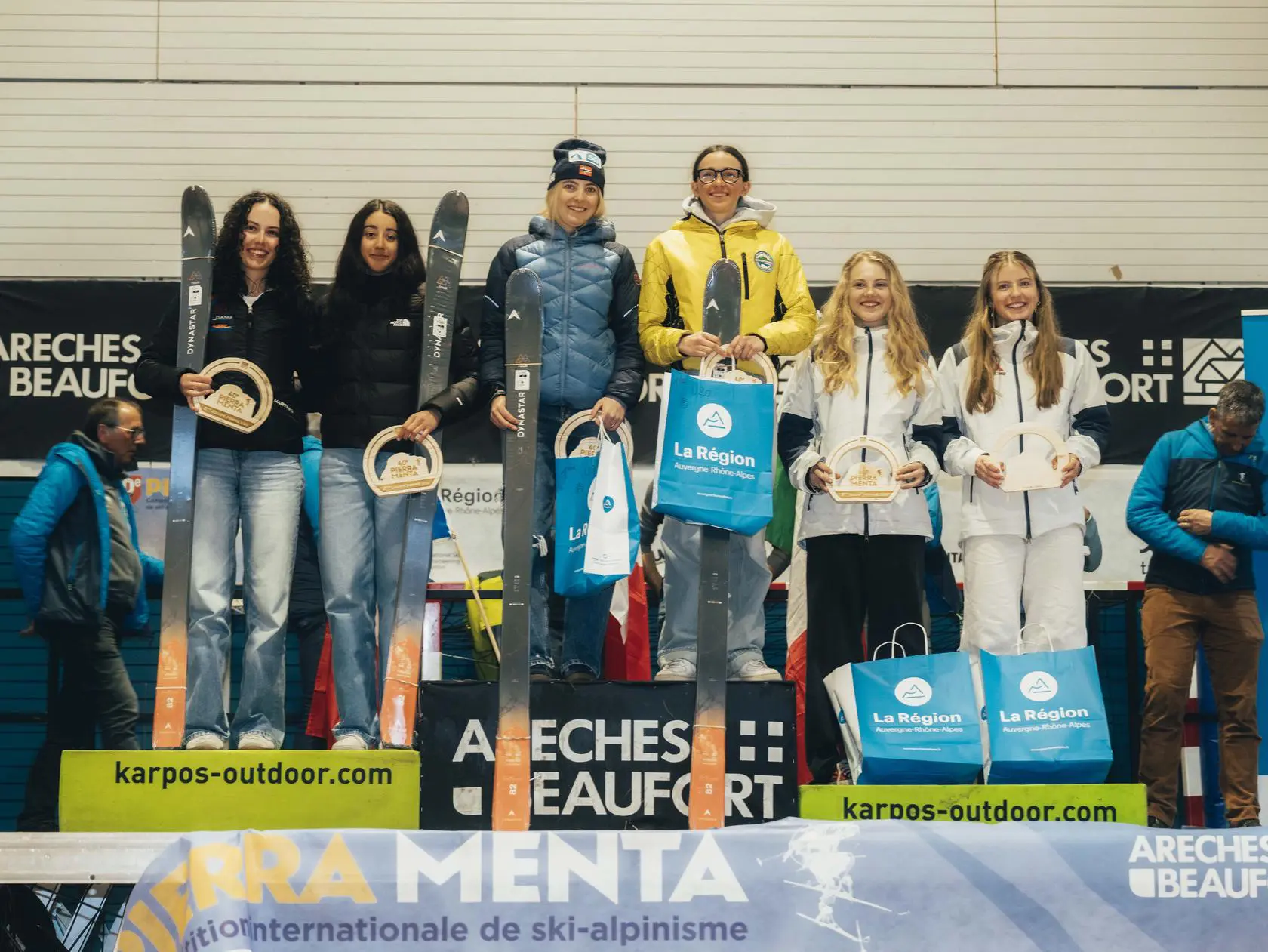 Female skiers celebrating on podium with skis.