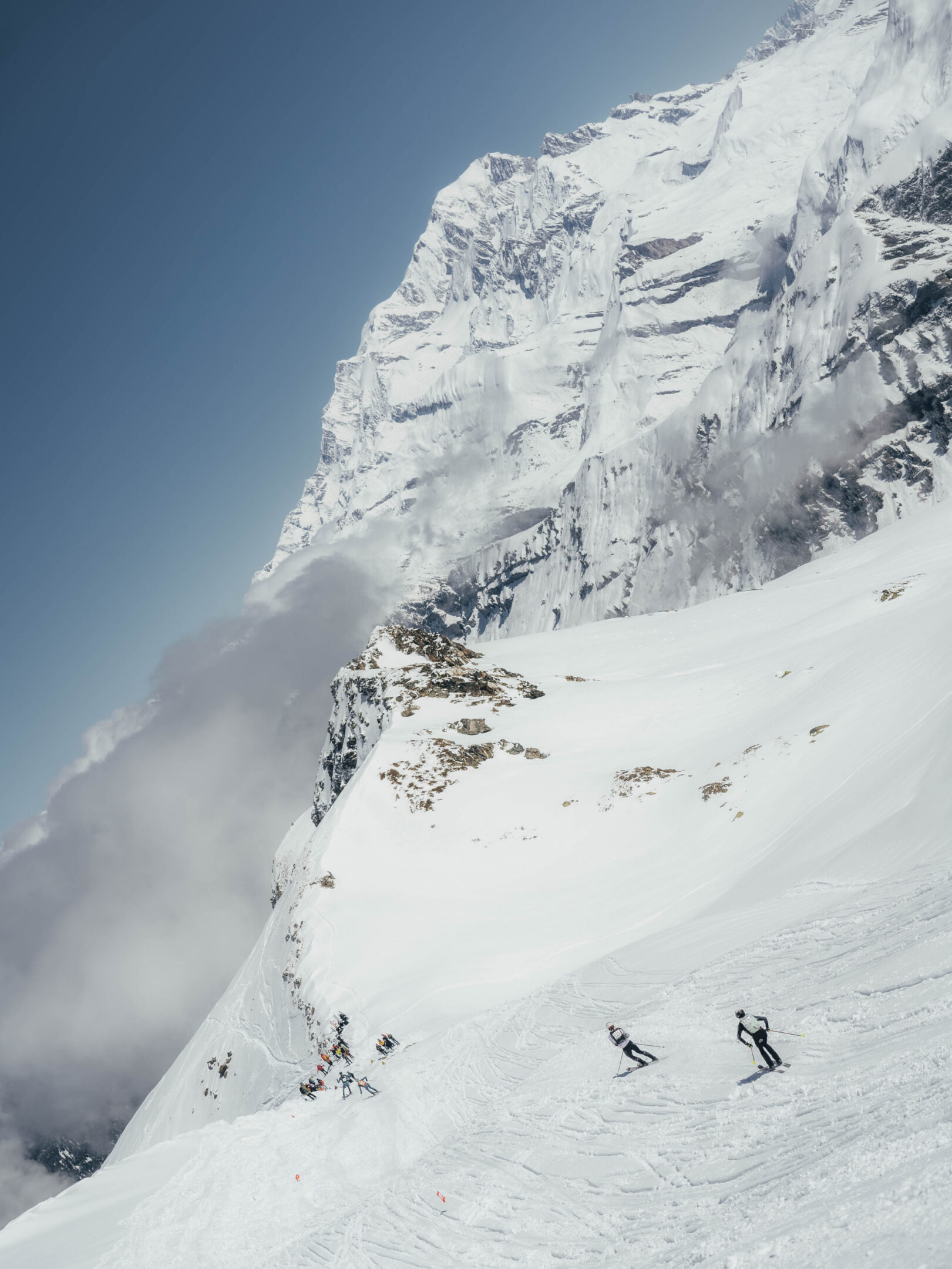 Skiers descending steep snowy mountain peak