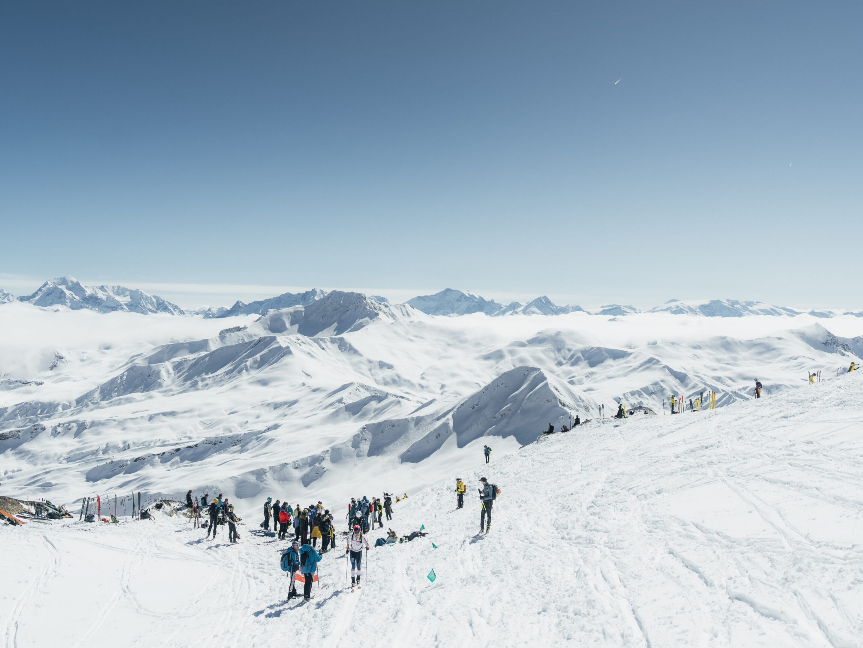 Winter landscape: skiers, snowy peaks, and cloudy valleys