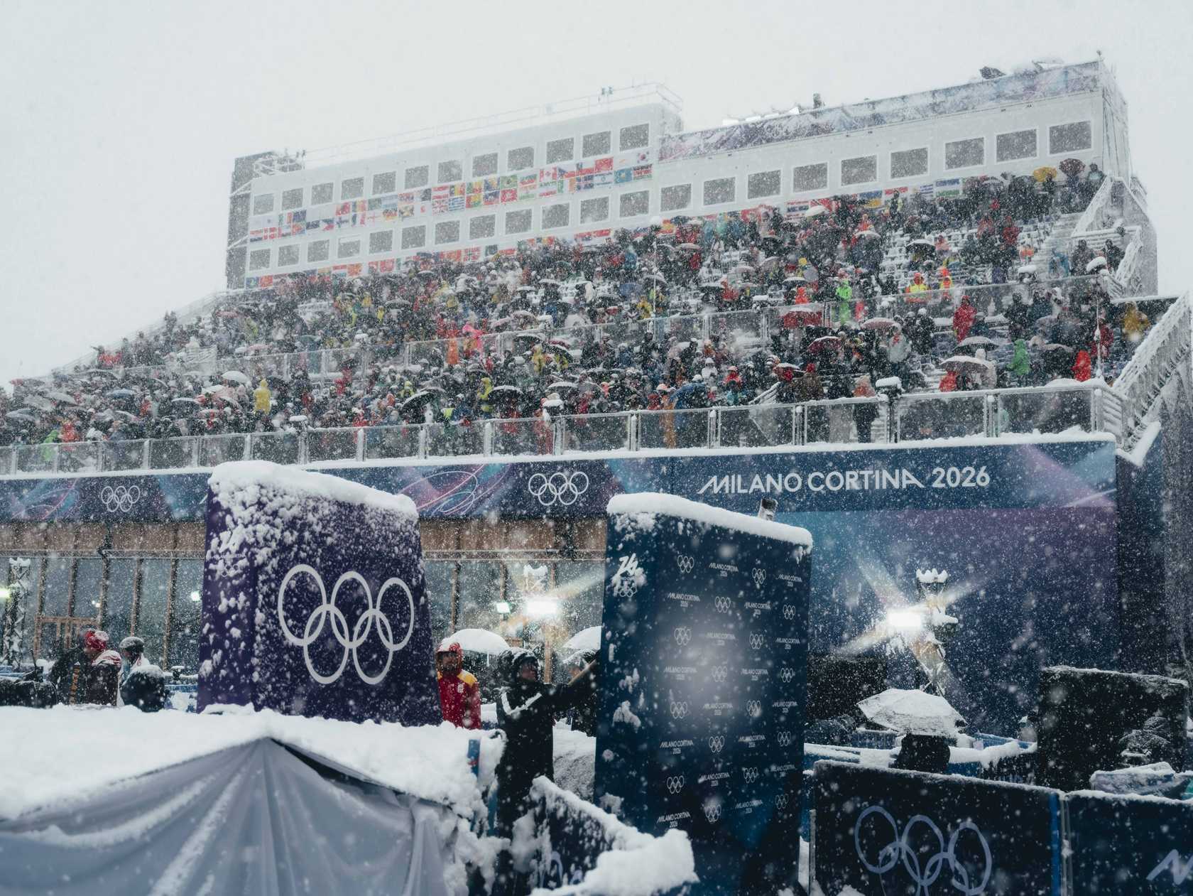 Large crowd of people standing in front of a building covered in snow, with banners, railings